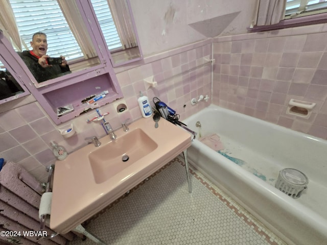 bathroom featuring a washtub, tile walls, and sink