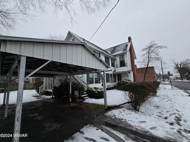 view of snowy exterior featuring a carport