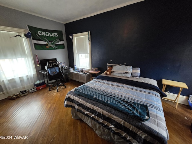 bedroom featuring wood-type flooring, multiple windows, and ornamental molding