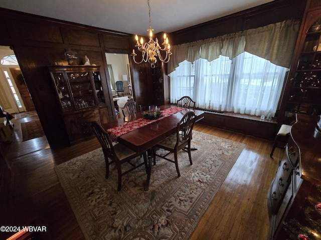 dining space with a notable chandelier, wood-type flooring, and wooden walls