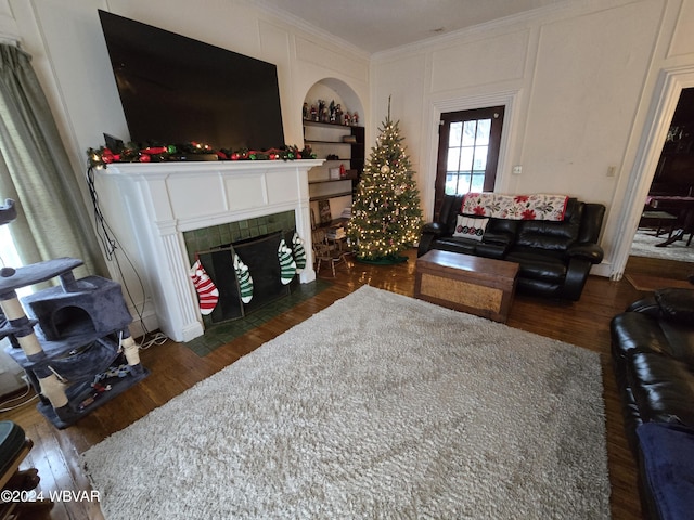 living room with dark hardwood / wood-style floors, ornamental molding, and a tile fireplace