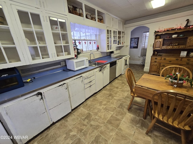 kitchen with white appliances, white cabinetry, crown molding, and sink