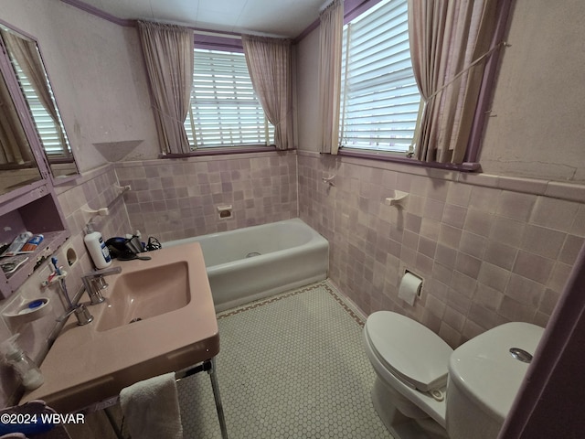 bathroom featuring a washtub, toilet, tile walls, and sink