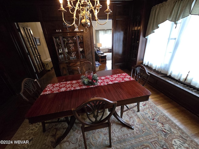 dining area with hardwood / wood-style floors, a notable chandelier, and wood walls