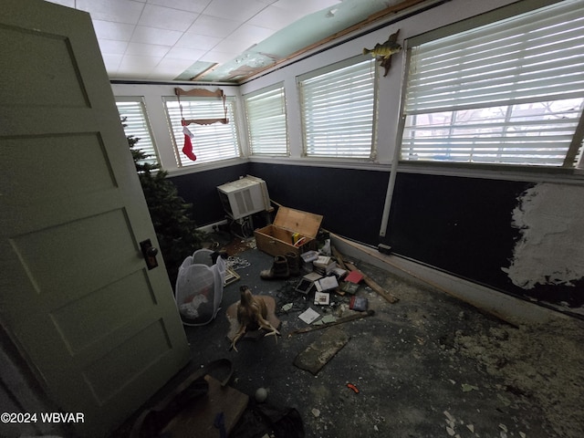 unfurnished sunroom featuring an AC wall unit and a wealth of natural light