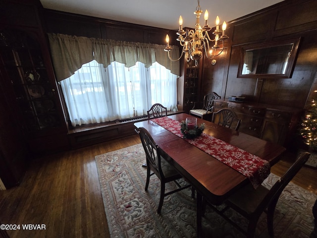 dining area featuring an inviting chandelier, dark wood-type flooring, and wood walls