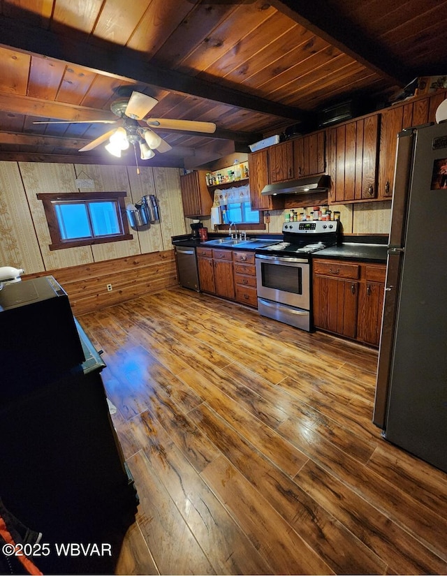 kitchen with beamed ceiling, appliances with stainless steel finishes, sink, and light hardwood / wood-style flooring