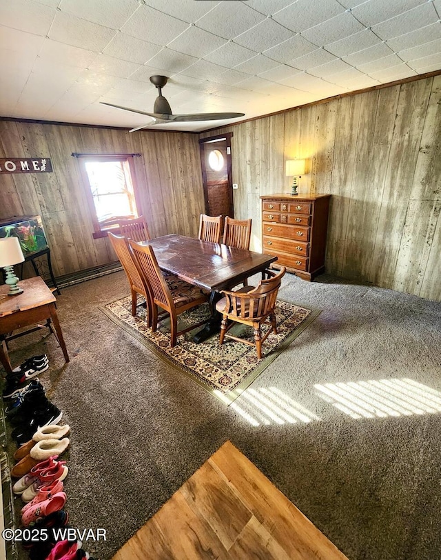 dining area featuring hardwood / wood-style flooring, ceiling fan, and wood walls