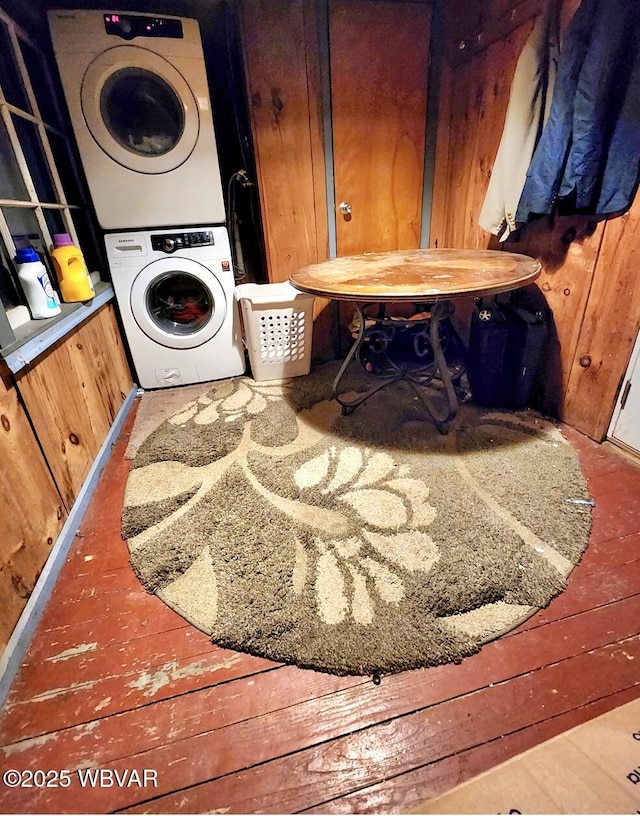 washroom with stacked washer and dryer and wood walls