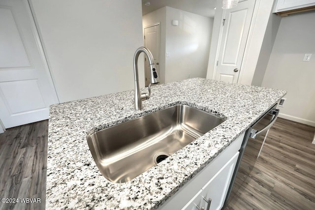 interior details featuring light stone countertops, sink, and dark wood-type flooring