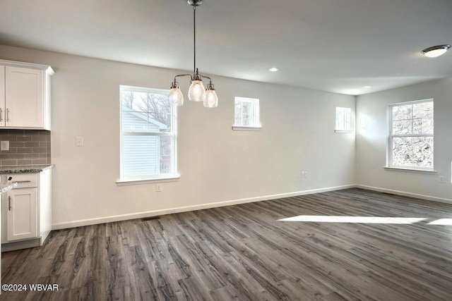 unfurnished dining area with a chandelier and dark hardwood / wood-style floors