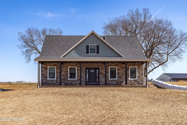 view of front of house with stone siding, covered porch, and a shingled roof