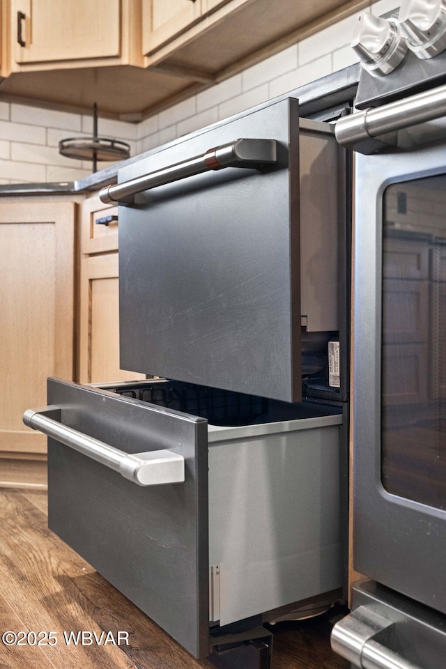 room details with oven, decorative backsplash, dark countertops, and wood finished floors