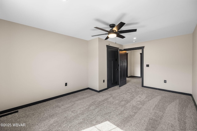 empty room featuring light colored carpet, baseboards, and ceiling fan