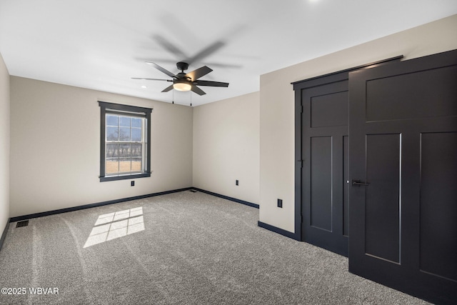 unfurnished bedroom with carpet flooring, visible vents, baseboards, and ceiling fan