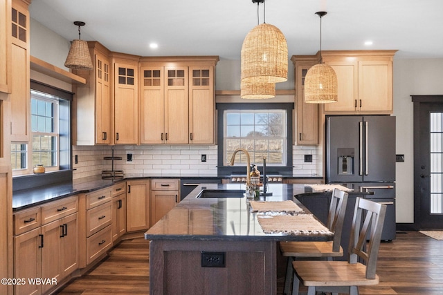 kitchen featuring a breakfast bar area, dark wood-style flooring, a sink, stainless steel refrigerator with ice dispenser, and tasteful backsplash