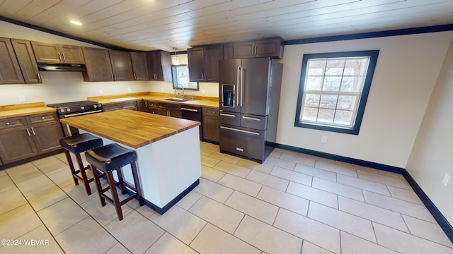 kitchen featuring sink, wooden counters, a kitchen bar, high quality appliances, and a kitchen island