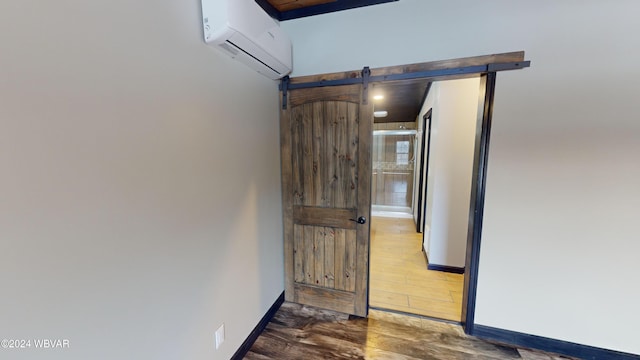 hall featuring a wall unit AC, a barn door, and dark hardwood / wood-style floors