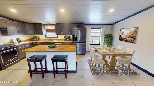 kitchen with sink, a kitchen breakfast bar, wooden counters, a kitchen island, and appliances with stainless steel finishes