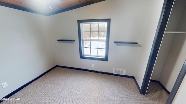 carpeted empty room with lofted ceiling