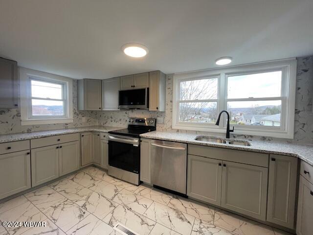 kitchen with sink, light stone countertops, and stainless steel appliances