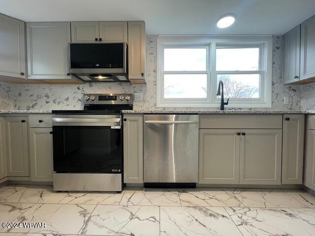 kitchen featuring gray cabinets, sink, light stone countertops, and stainless steel appliances