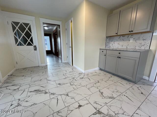 kitchen with light stone counters and gray cabinetry