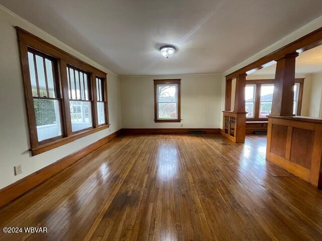 spare room with decorative columns, ornamental molding, and hardwood / wood-style flooring