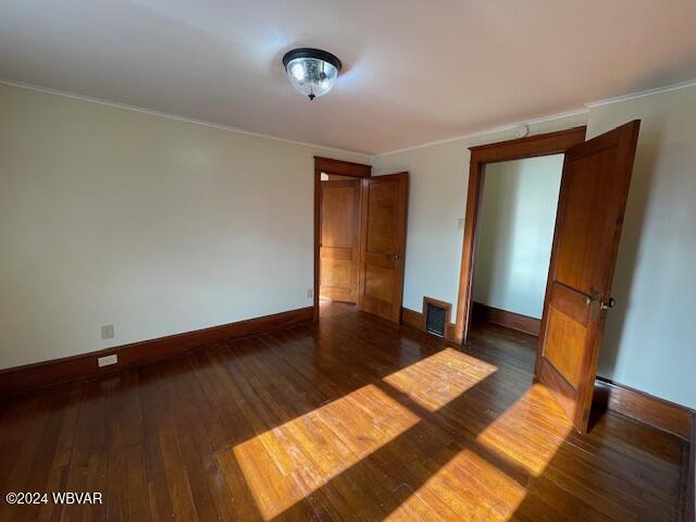 unfurnished bedroom featuring crown molding and dark hardwood / wood-style floors