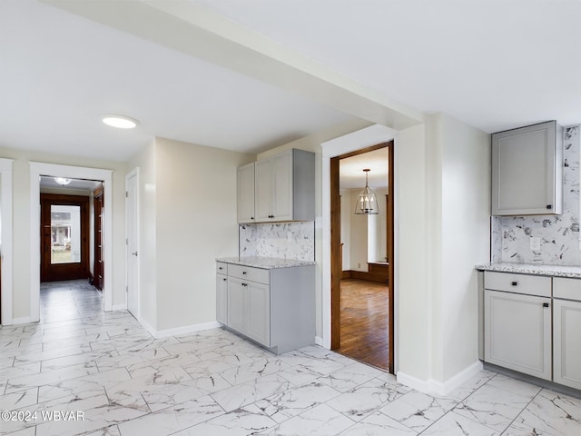 kitchen with gray cabinets, light stone countertops, light hardwood / wood-style flooring, and tasteful backsplash