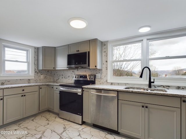 kitchen with appliances with stainless steel finishes, gray cabinets, a healthy amount of sunlight, and sink