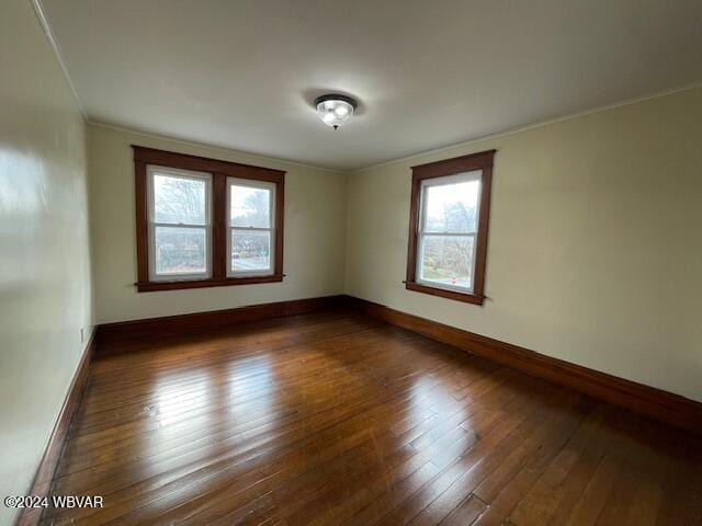 empty room featuring ornamental molding, dark hardwood / wood-style flooring, and a healthy amount of sunlight