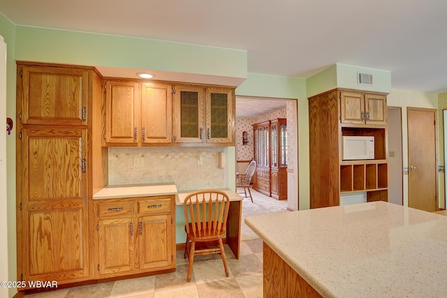 43 Hillcrest Ln, Williamsport, PA 17701 - kitchen featuring white microwave, glass insert cabinets, decorative backsplash, wallpapered walls, and brown cabinets