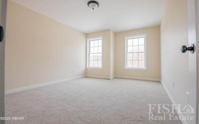 spare room with baseboards and light colored carpet