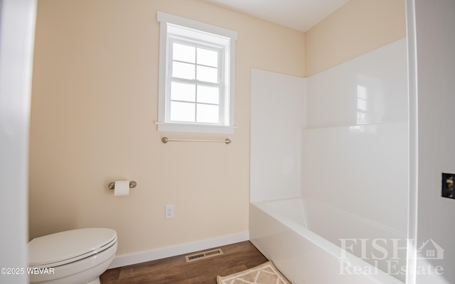 bathroom featuring a tub to relax in, visible vents, baseboards, toilet, and wood finished floors