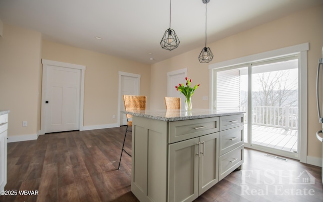 kitchen featuring light stone counters, a breakfast bar area, visible vents, a center island, and pendant lighting