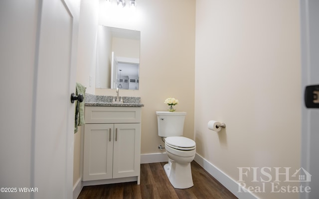 bathroom with wood finished floors, vanity, toilet, and baseboards