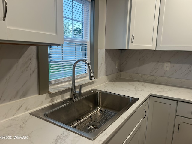 2401 Linn St, Williamsport, PA 17701 - kitchen with white cabinetry, light stone counters, tasteful backsplash, and a sink