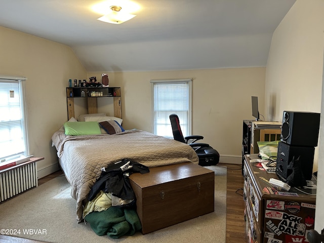 bedroom with lofted ceiling, radiator heating unit, and light hardwood / wood-style flooring