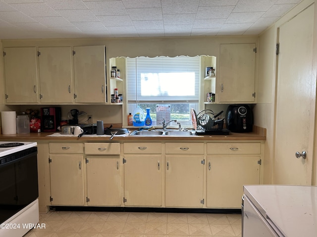 kitchen featuring white range with electric stovetop, sink, and cream cabinets