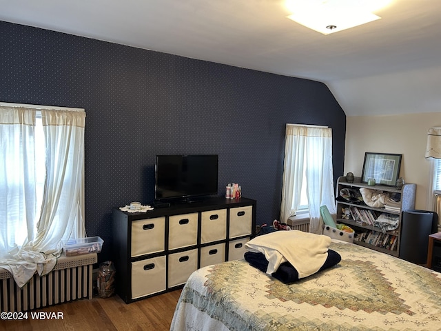 bedroom featuring hardwood / wood-style flooring, radiator, and vaulted ceiling