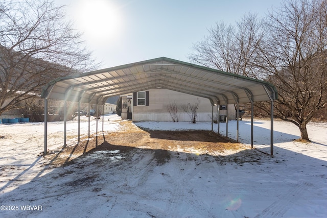 snow covered parking area with a carport