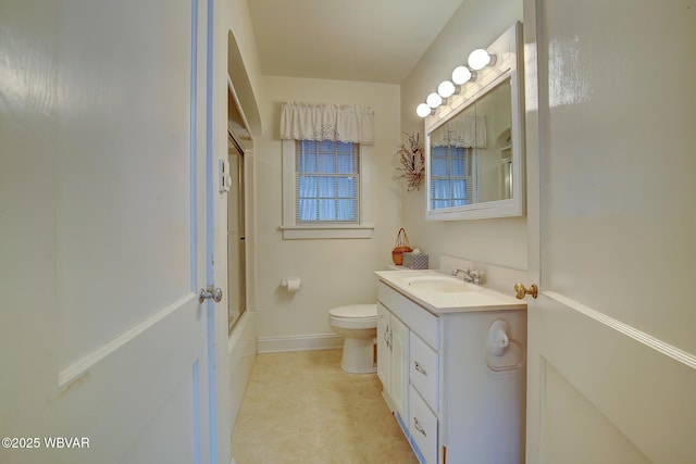 bathroom with baseboards, enclosed tub / shower combo, vanity, and toilet