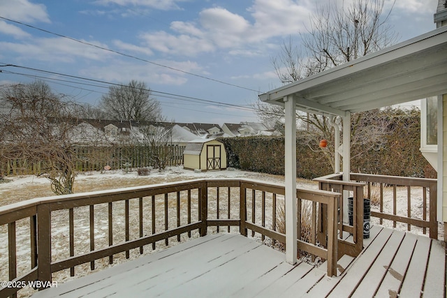 snow covered deck with central AC unit, a storage unit, and an outdoor structure