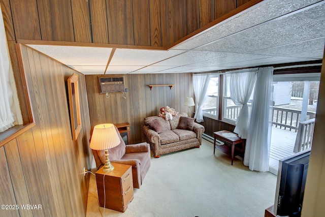 carpeted living room with baseboard heating, wood walls, and a wall unit AC