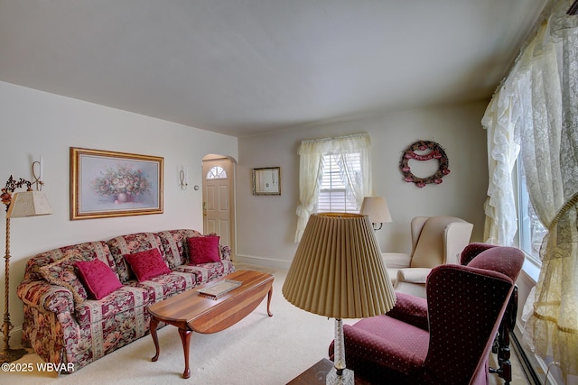 living area featuring arched walkways, carpet flooring, and baseboards