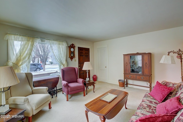 living room with a baseboard heating unit and light colored carpet