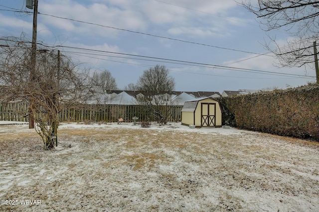 yard layered in snow with an outbuilding, fence, and a storage shed