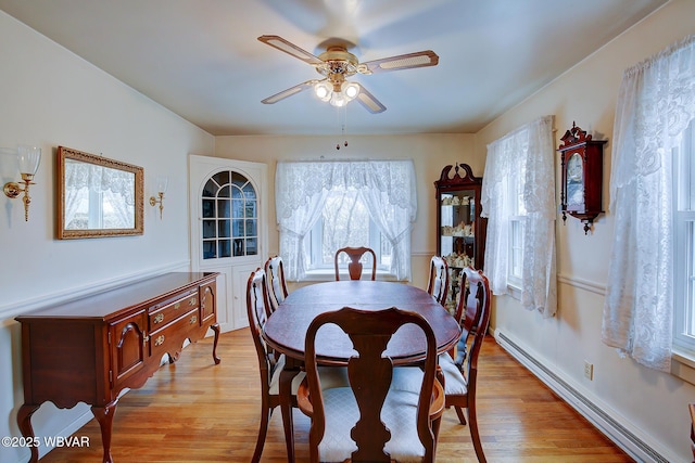 dining space with light wood-type flooring, a baseboard radiator, and a ceiling fan