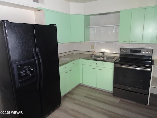 kitchen with light wood-type flooring, black fridge with ice dispenser, sink, stainless steel electric range oven, and green cabinets